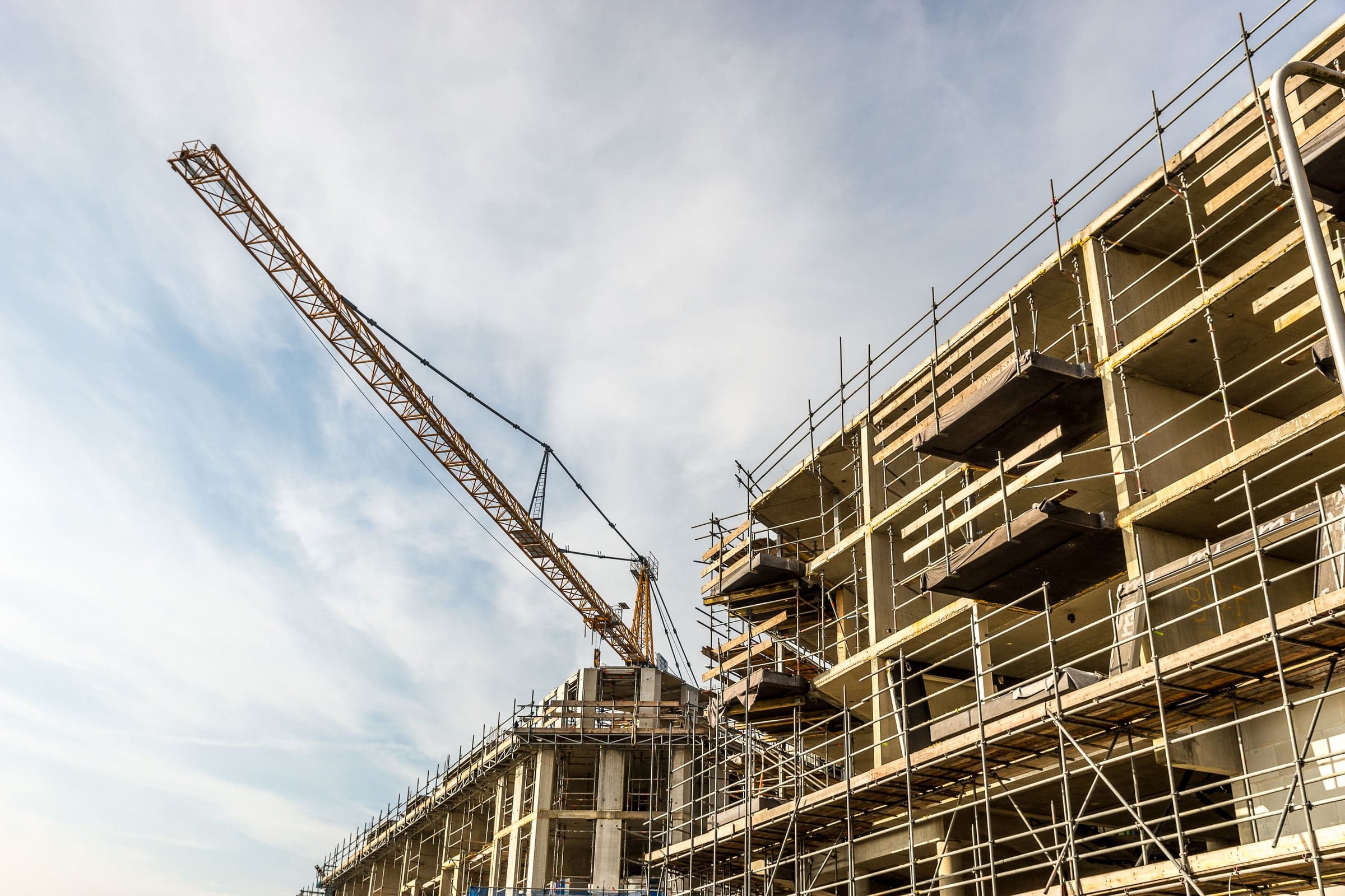Tower crane above a concrete-frame building shell with scaffolding